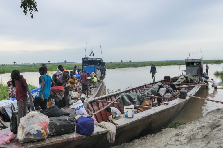 Newly arrived, men, women and children, arriving from Renk offload their luggage from a boat in Bulukat port in Malakal, Upper Nile State in South Sudan. The Bulukat transit centre hosts over 5,000 returnees who fled the conflict in Sudan.