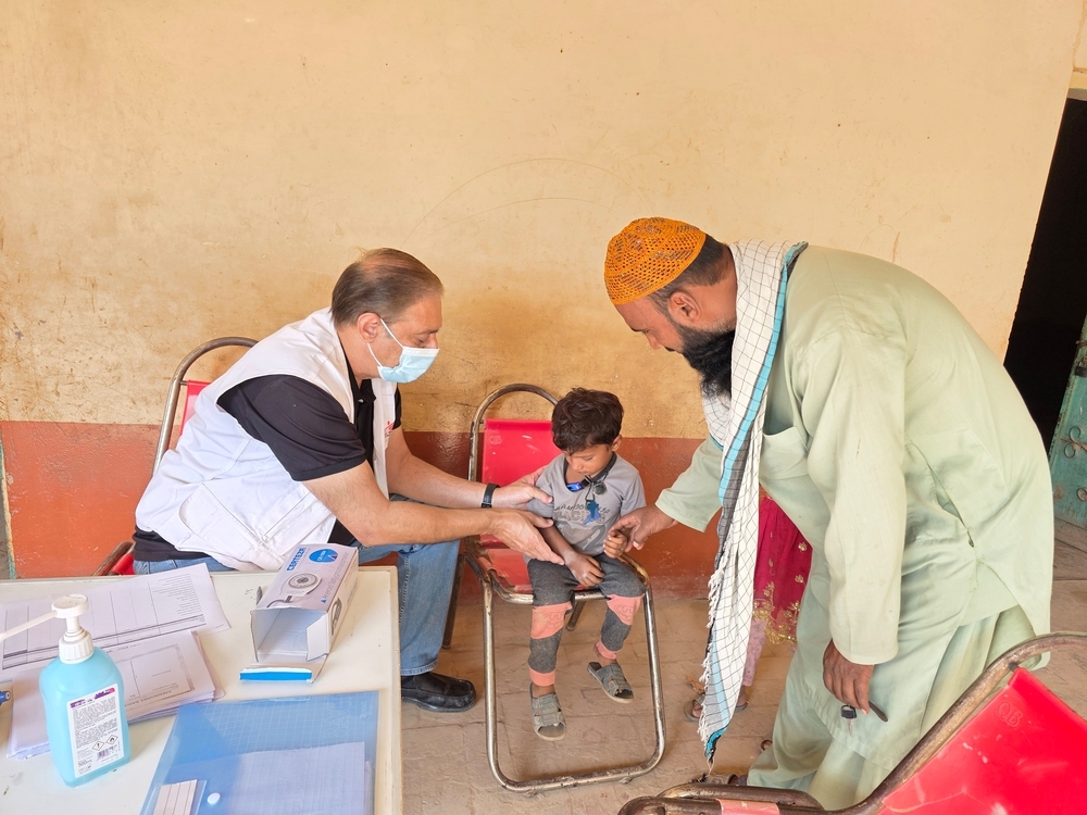 An MSF doctor checks a child's temperature during a mobile clinic consultation in Tibbi Sohrab, Jalalpur Pirwala, Multan District. ©️Gul Nayab/MSF